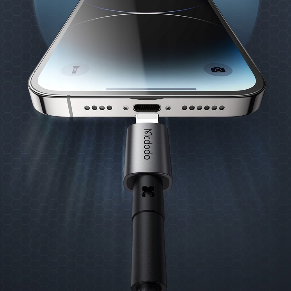 Primo piano di uno smartphone collegato a un cavo di ricarica grigio.