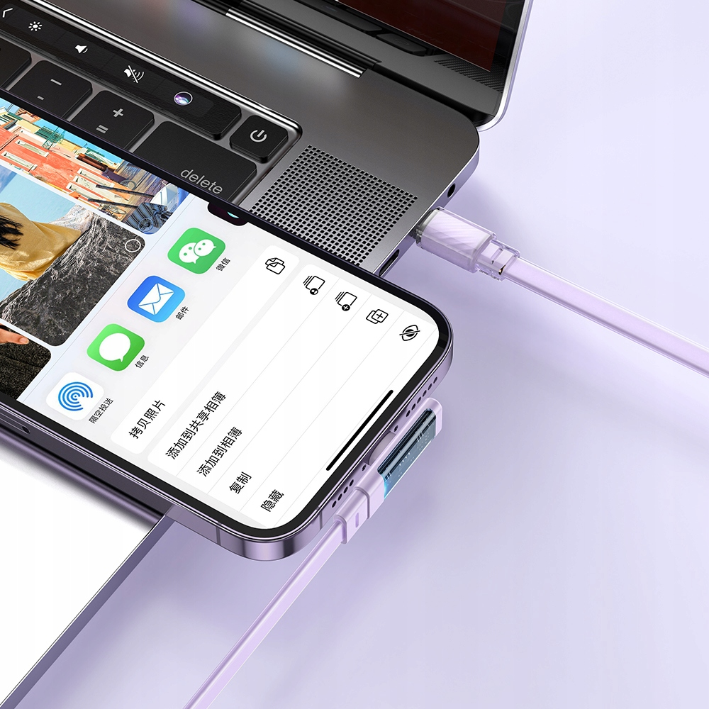 Uno smartphone e un laptop collegati con cavi viola su una superficie viola.