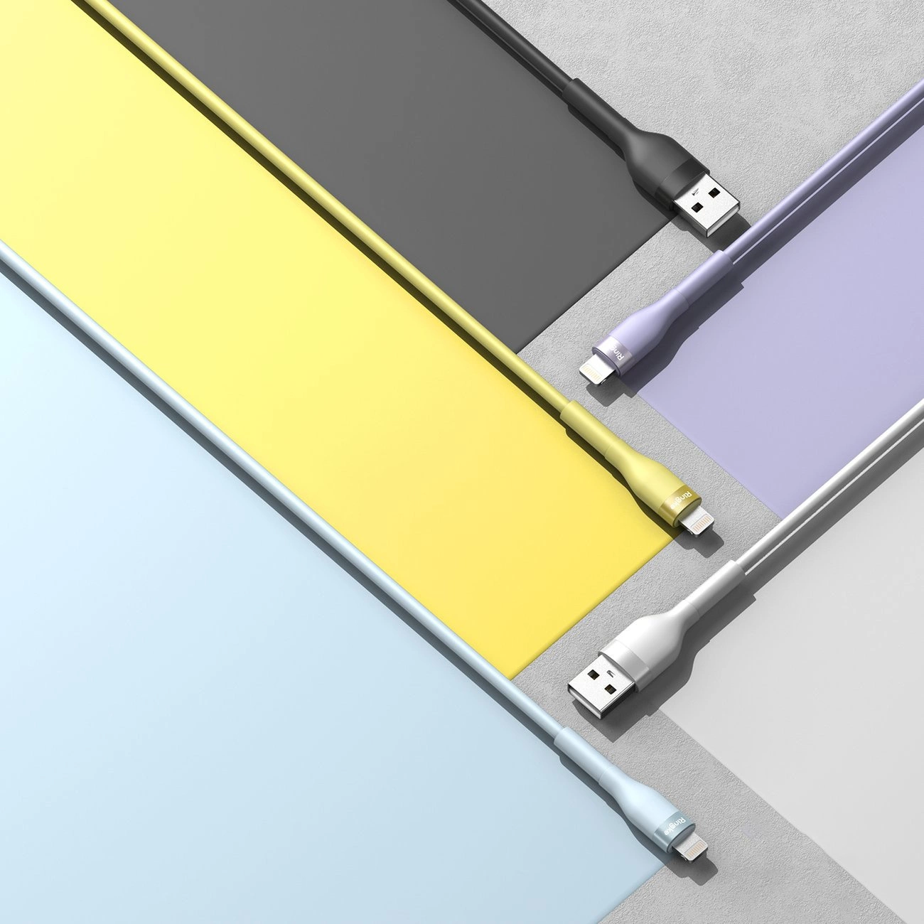 Quattro cavi di ricarica colorati in nero, viola, giallo e blu su superfici abbinate.