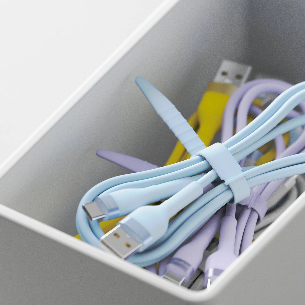 Vari cavi USB colorati legati e riordinati ordinatamente all'interno di una scatola grigia.