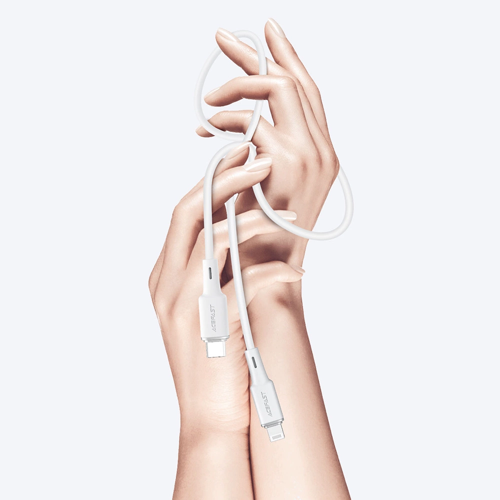 Due mani intrecciate tengono un cavo bianco da USB-C a Lightning su sfondo grigio chiaro.