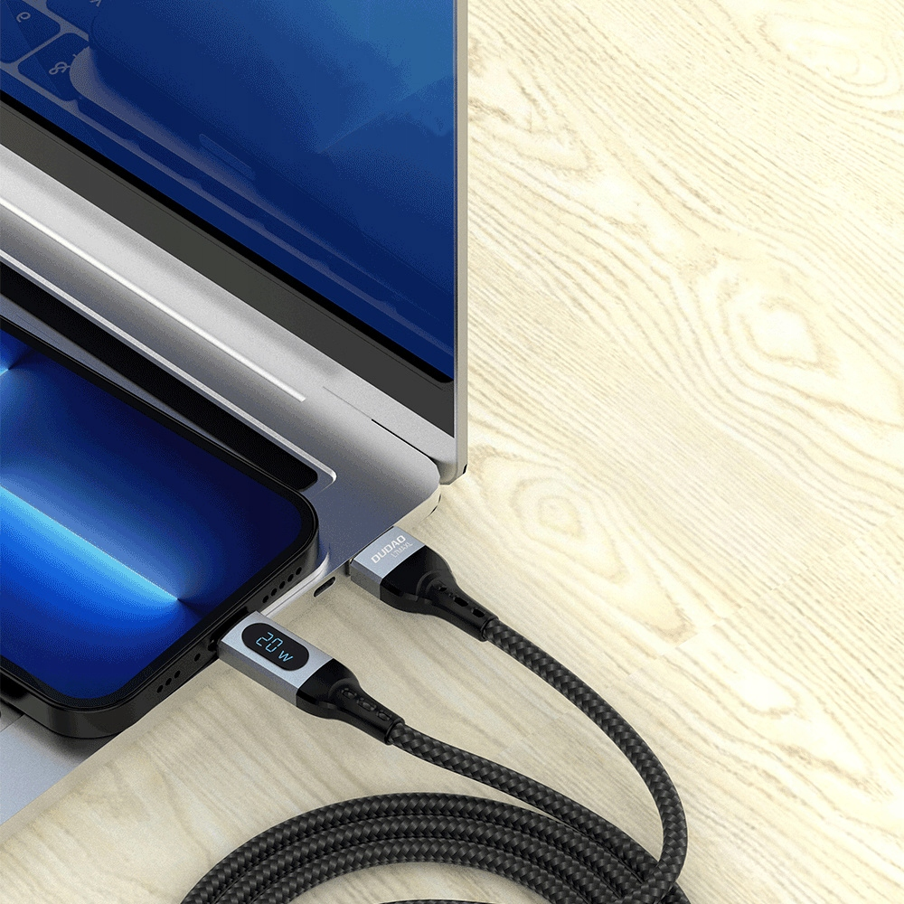 Uno smartphone e un computer portatile sono in carica con cavi USB intrecciati su una scrivania.