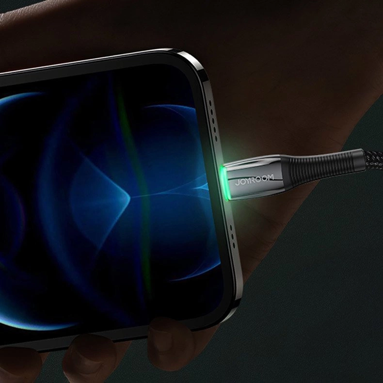 Un cavo Joyroom è collegato alla porta di ricarica di uno smartphone, brillando di luce verde.
