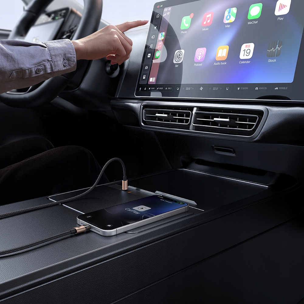 Mano tocca il touchscreen dell'auto mentre uno smartphone è collegato alla console centrale.