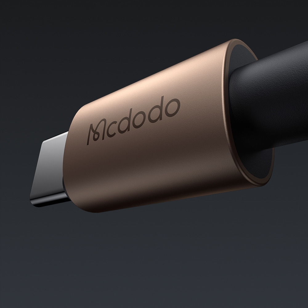 Primo piano di un connettore per cavo USB-C Mcdodo color bronzo su sfondo grigio scuro.
