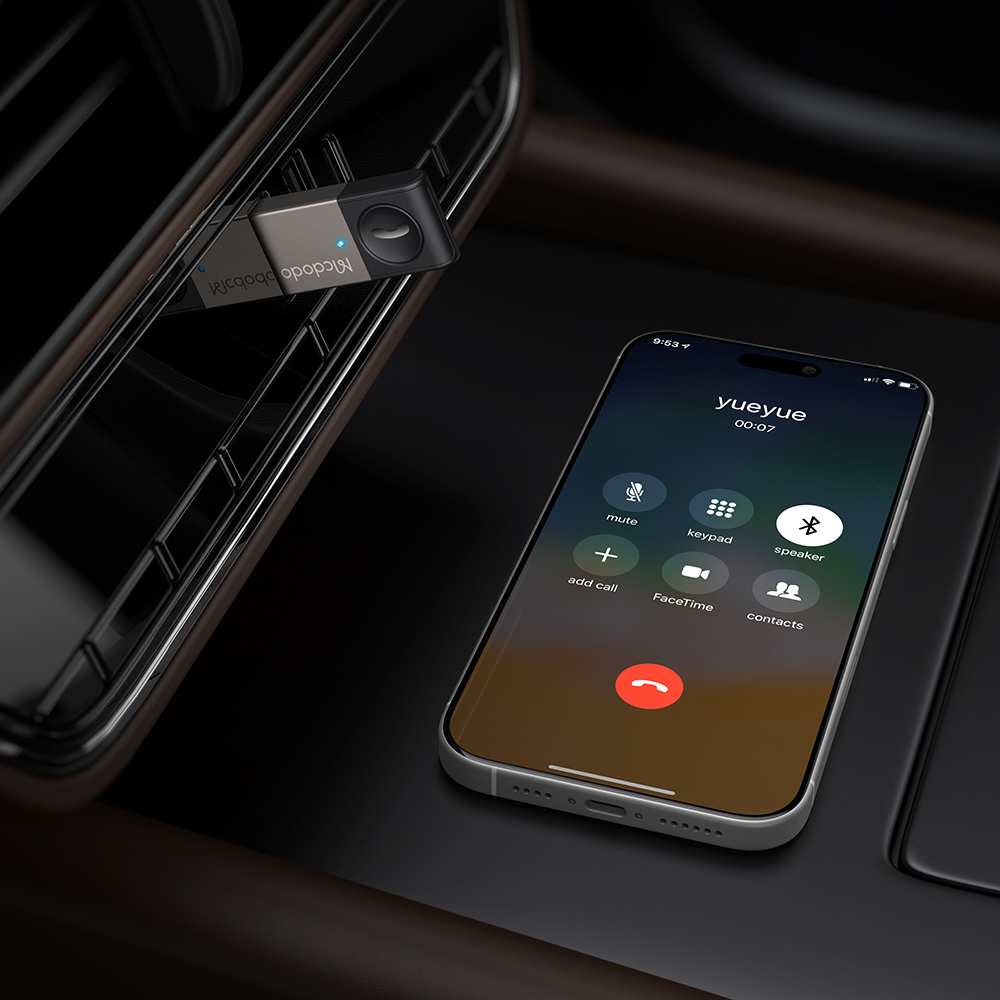 Uno smartphone in chiamata si trova su una console accanto a un adattatore USB in una bocchetta.