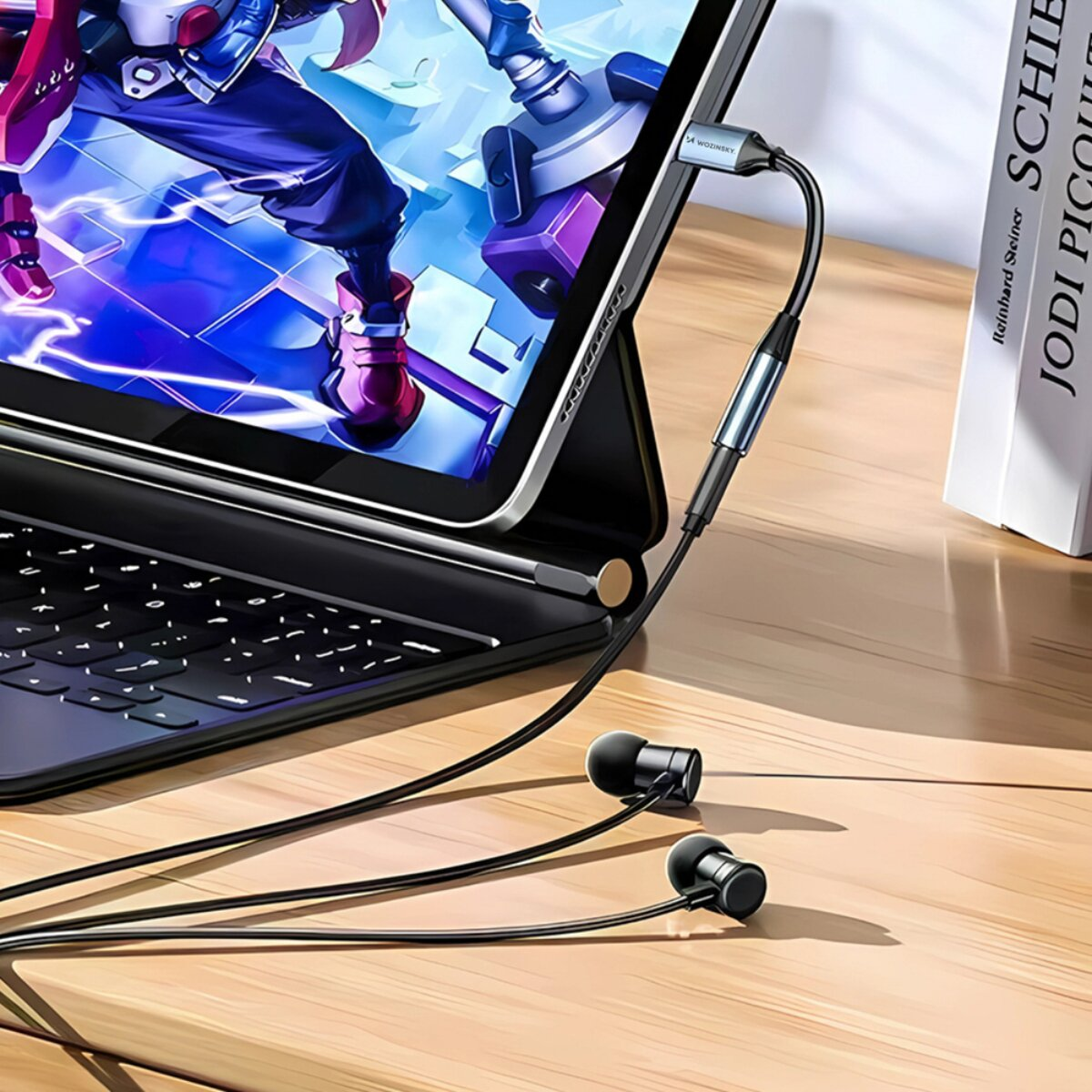 Auricolari con filo collegati tramite adattatore a un tablet su una scrivania in legno.