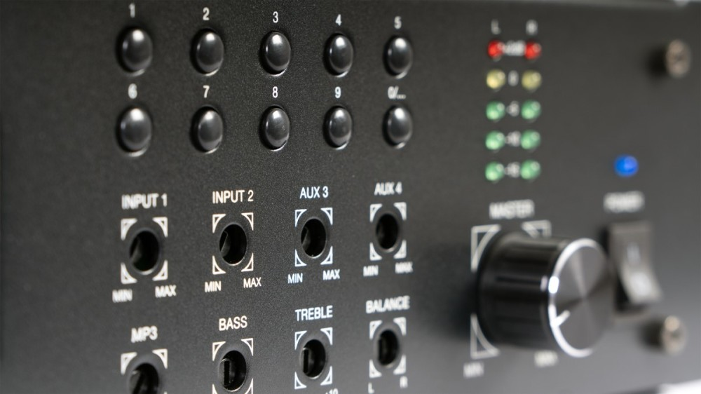 Czarny panel sterowania audio z numerowanymi przyciskami, gniazdami, pokrętłem i diodami.