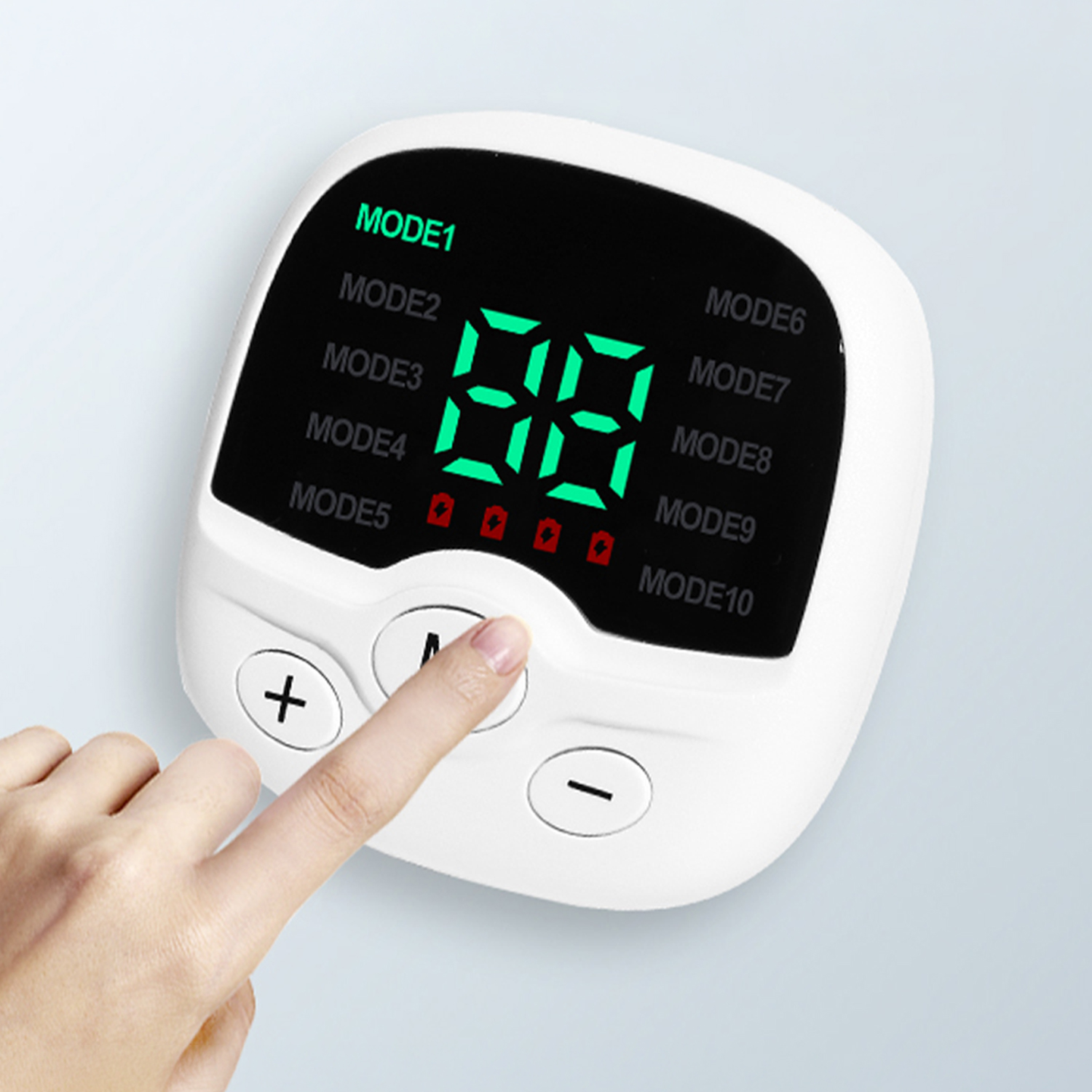 Un dedo presiona el botón M en un dispositivo electrónico blanco con una pantalla digital verde y modos del 1 al 10.