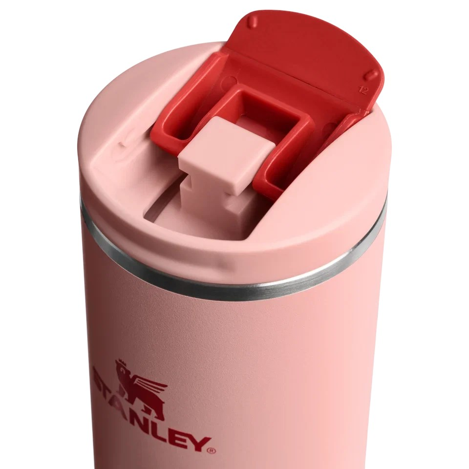 Beyaz arka planda kırmızı kapaklı ve Stanley logolu pembe seyahat kupası.
