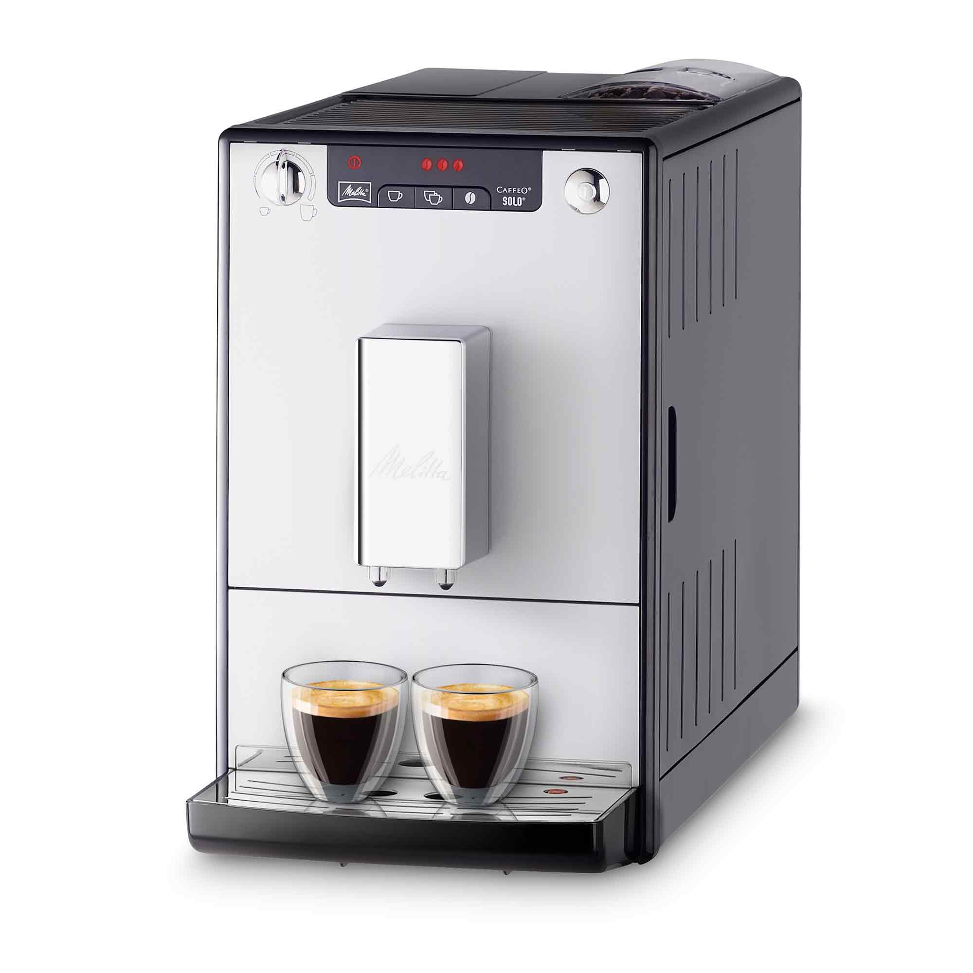 Moderna macchina da caffè nera e argento con due tazze di espresso sul vassoio raccogligocce su sfondo bianco.
