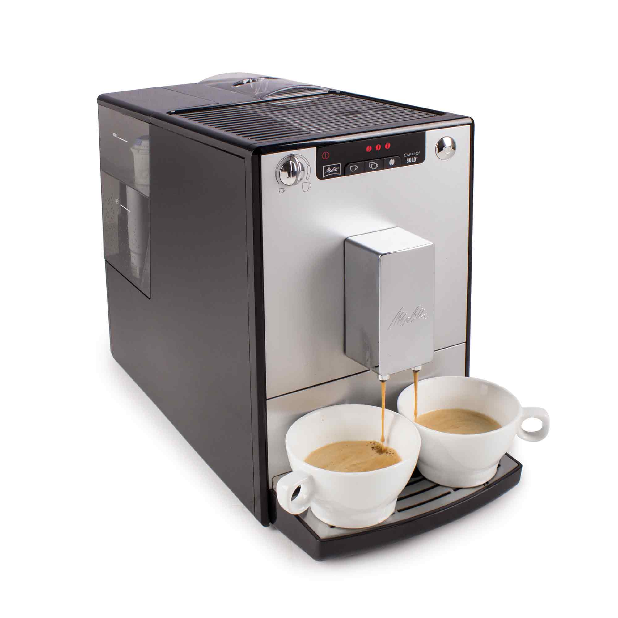 Una macchina da caffè nera e argento eroga caffè in due tazze bianche su sfondo bianco.