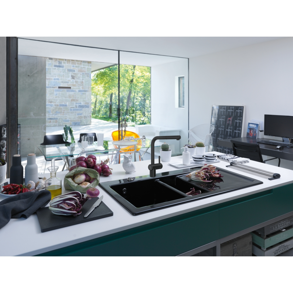 Cucina moderna con doppio lavello nero, verdure sul bancone e vista sul verde soleggiato esterno.