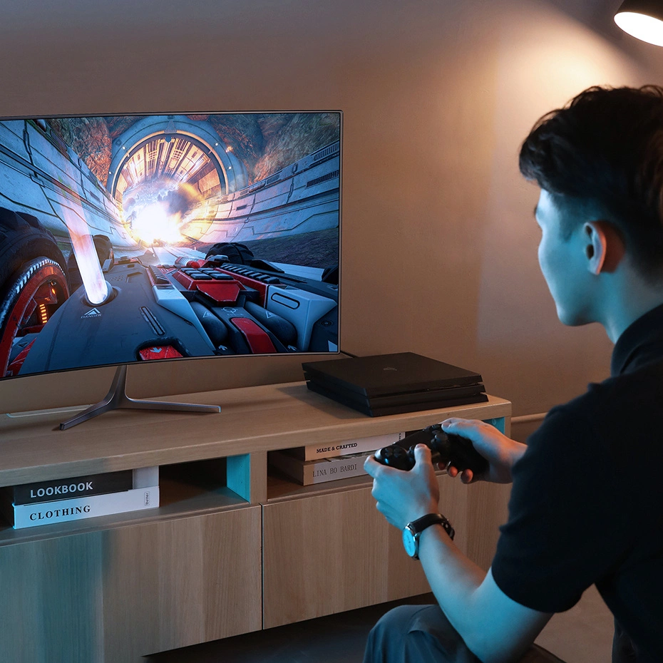 Un giovane gioca a un videogioco di corse futuristico su un grande schermo usando un controller nero.