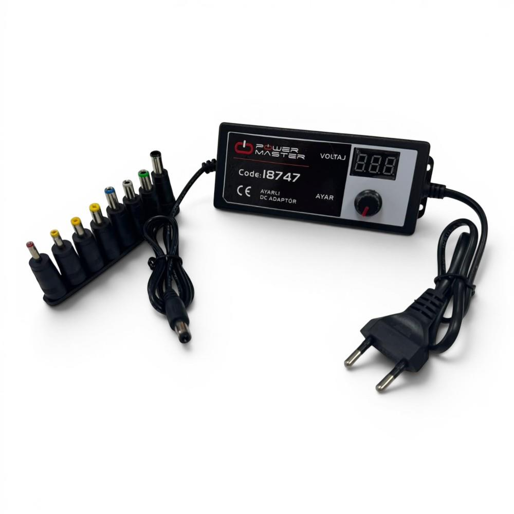 Beyaz zemin üzerinde dijital ekranlı ve çeşitli uçlara sahip ayarlanabilir DC adaptör.