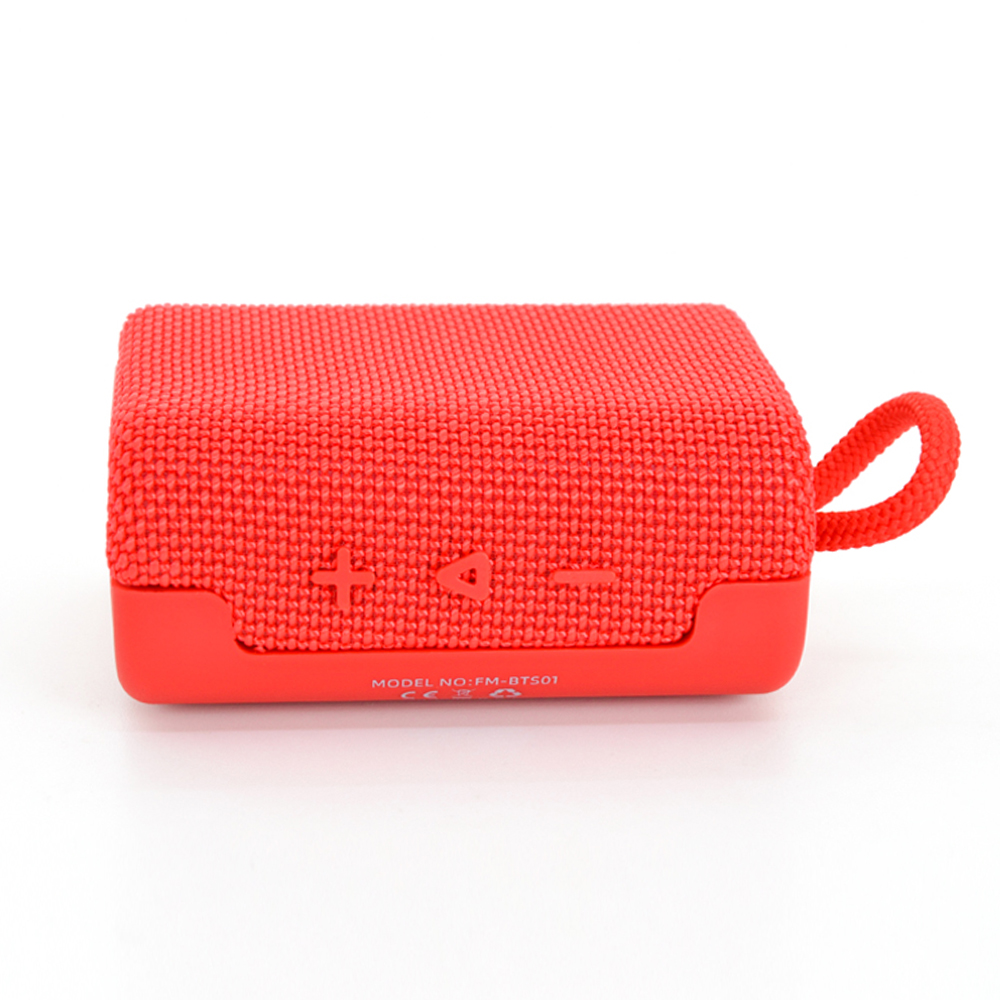 Beyaz arka planda kumaş kaplamalı ve taşıma askılı kırmızı taşınabilir Bluetooth hoparlör.