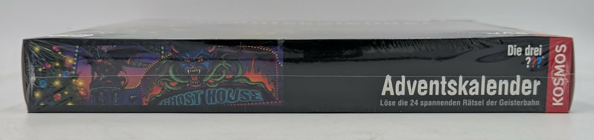 Seitenansicht einer schwarzen Ghost House Adventskalenderbox mit bunter Monsterkunst und deutschem Text.