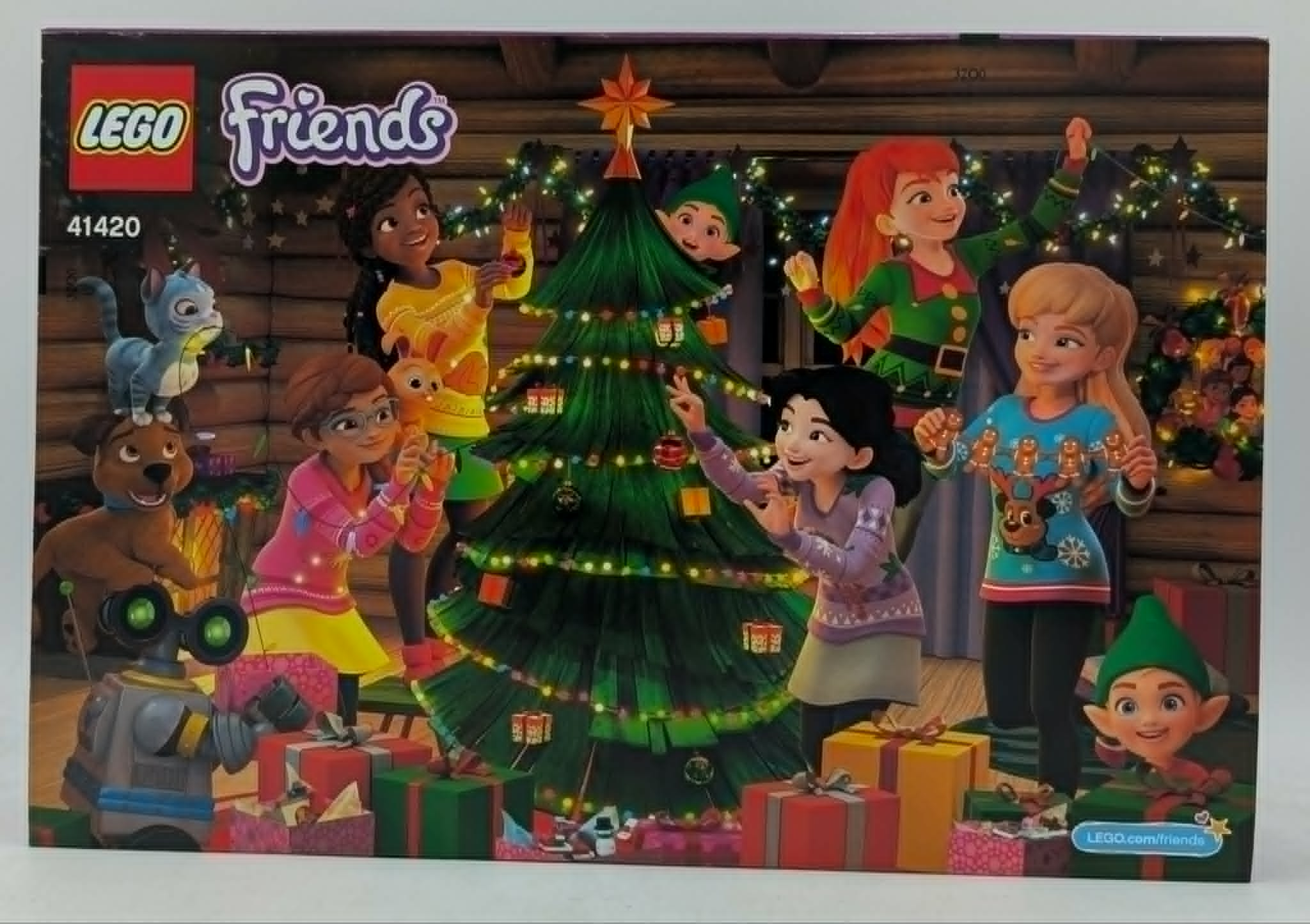 Lego-Friends-Figuren schmücken einen großen Weihnachtsbaum mit Lichtern und Geschenken.