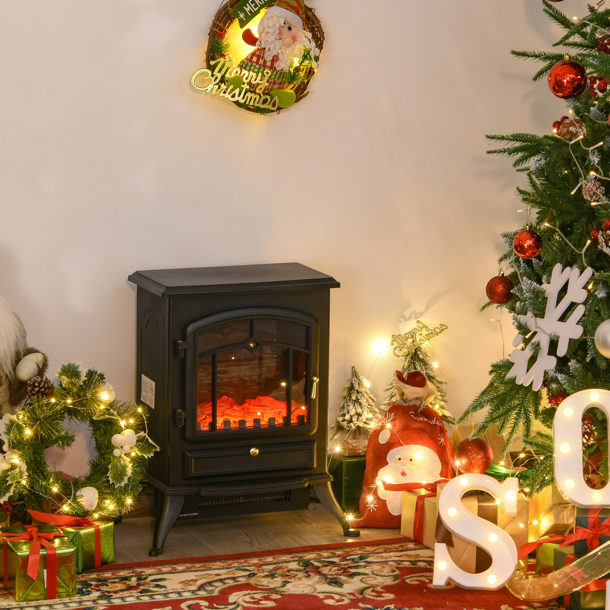 Una chimenea eléctrica en decoración navideña con corona iluminada, regalos y árbol.