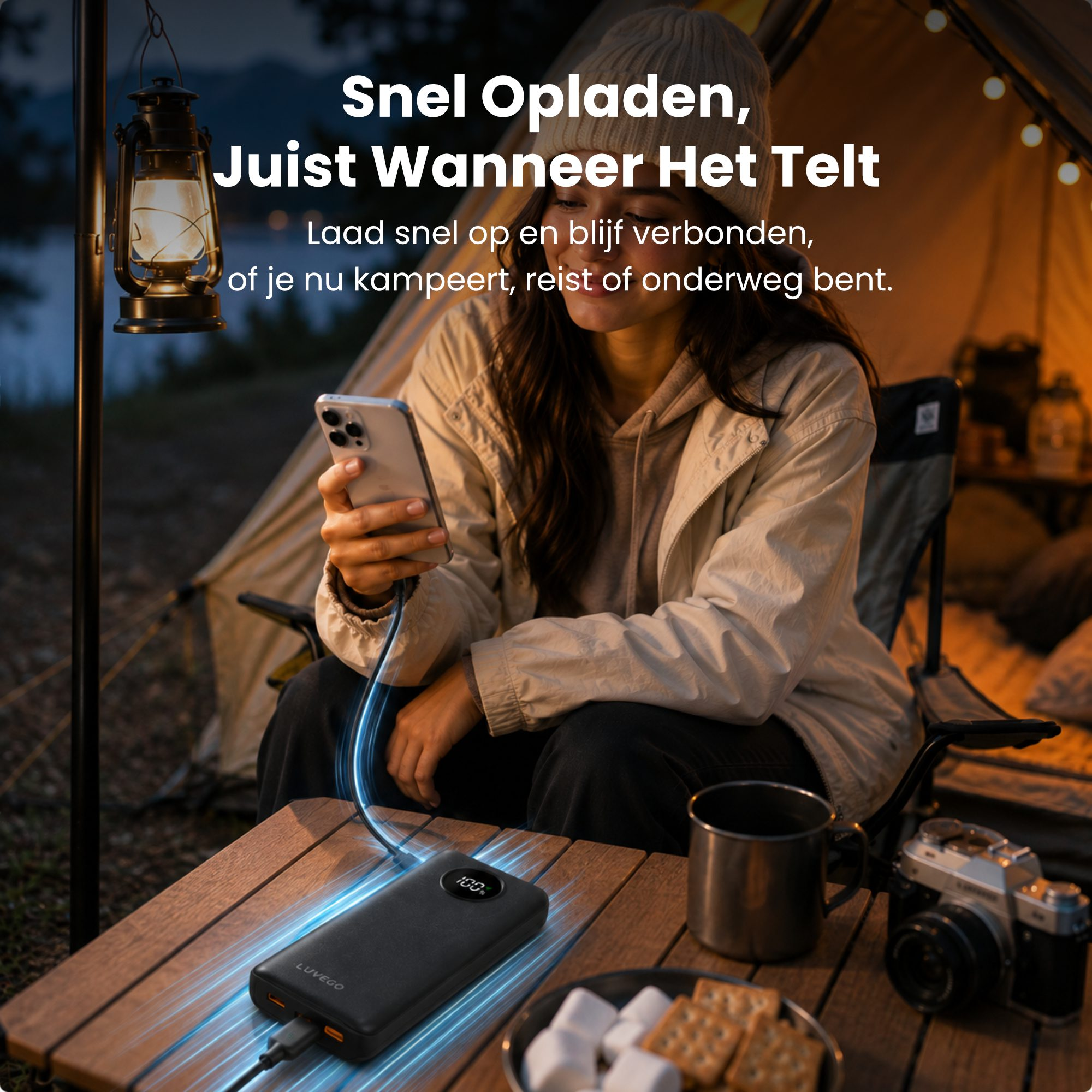 Frau sitzt im Zelt beim Camping und lädt ihr Smartphone an einer Powerbank auf einem Holztisch.