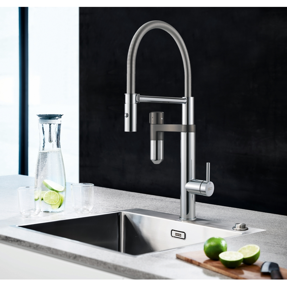 Moderno rubinetto da cucina in cromo su lavello con caraffa d'acqua e lime freschi.
