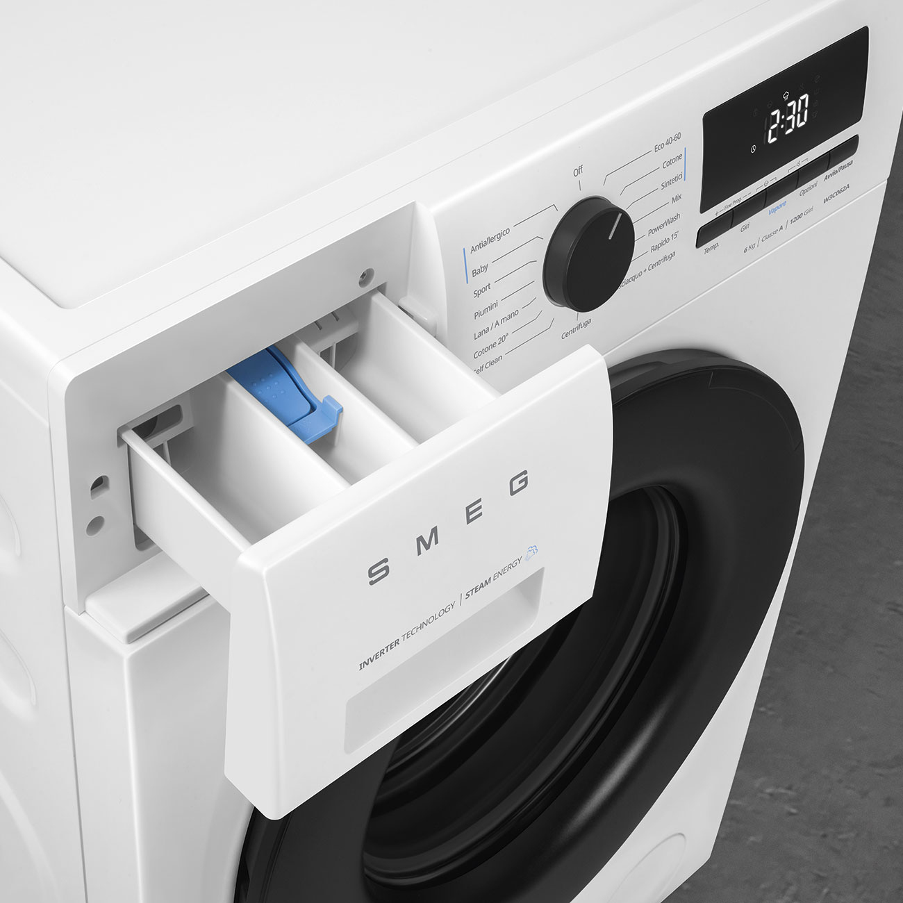 Una lavatrice bianca SMEG con il cassetto del detersivo aperto, una manopola nera e un display digitale.