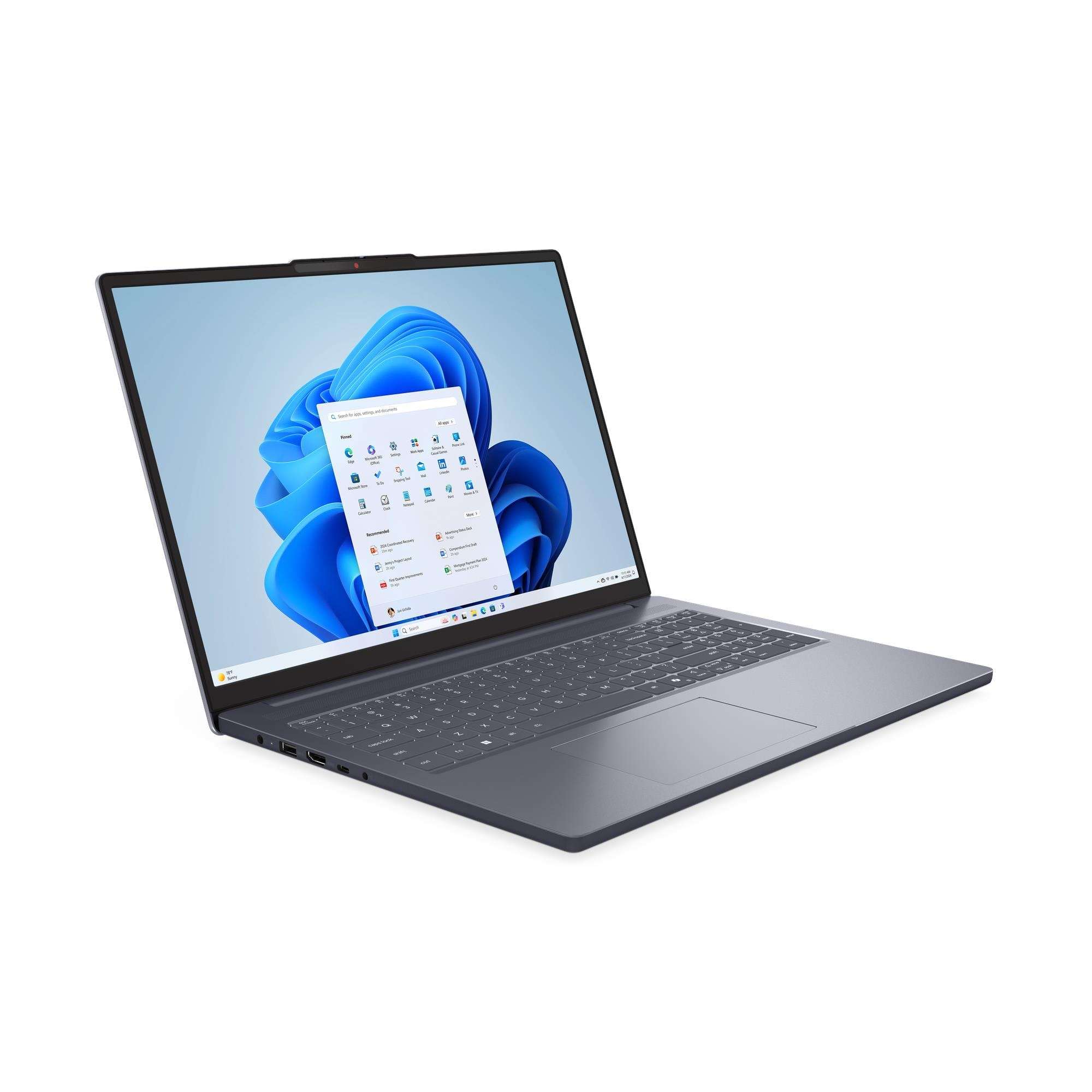 Şık, koyu gri bir dizüstü bilgisayar beyaz bir yüzeyde açık ve Windows 11 başlat menüsünü gösteriyor.