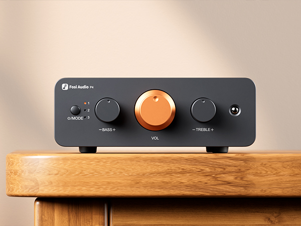 Ein schwarzer Fosi Audio P4 Verstärker mit einem orangen Lautstärkeregler steht auf Holz.