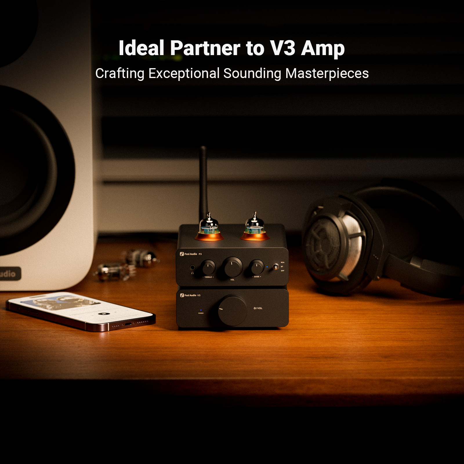 Un dispositivo de audio negro con tubos brillantes en una mesa de madera, con altavoz, teléfono y auriculares.