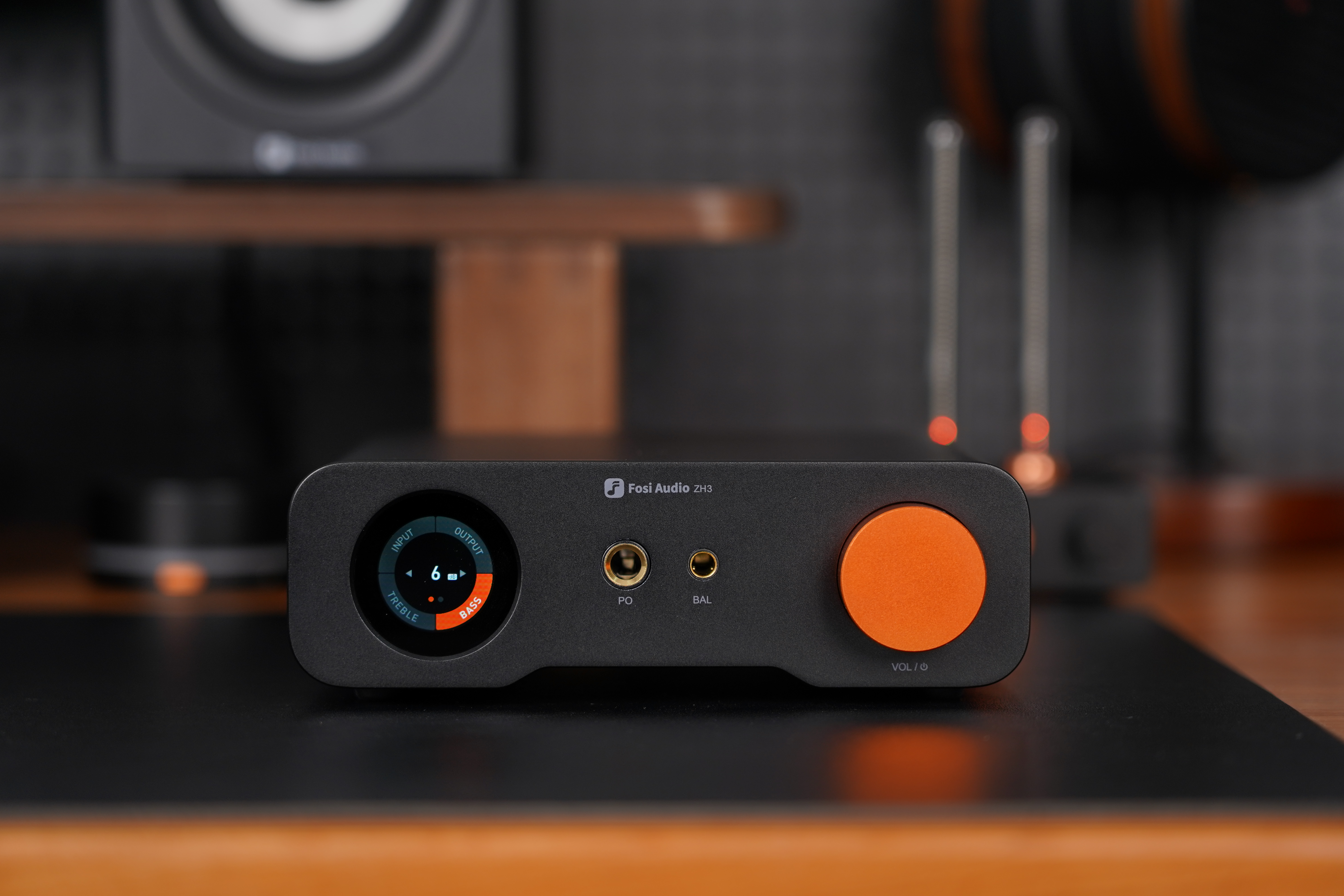 Schwarzer Fosi Audio ZH3 Verstärker mit rundem Display, Kopfhörerbuchsen und einem orangefarbenen Lautstärkeregler.