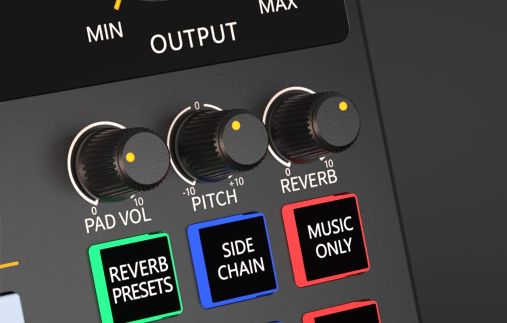 Primo piano di una console audio con tre manopole per volume, tonalità e riverbero, e pulsanti funzione colorati.