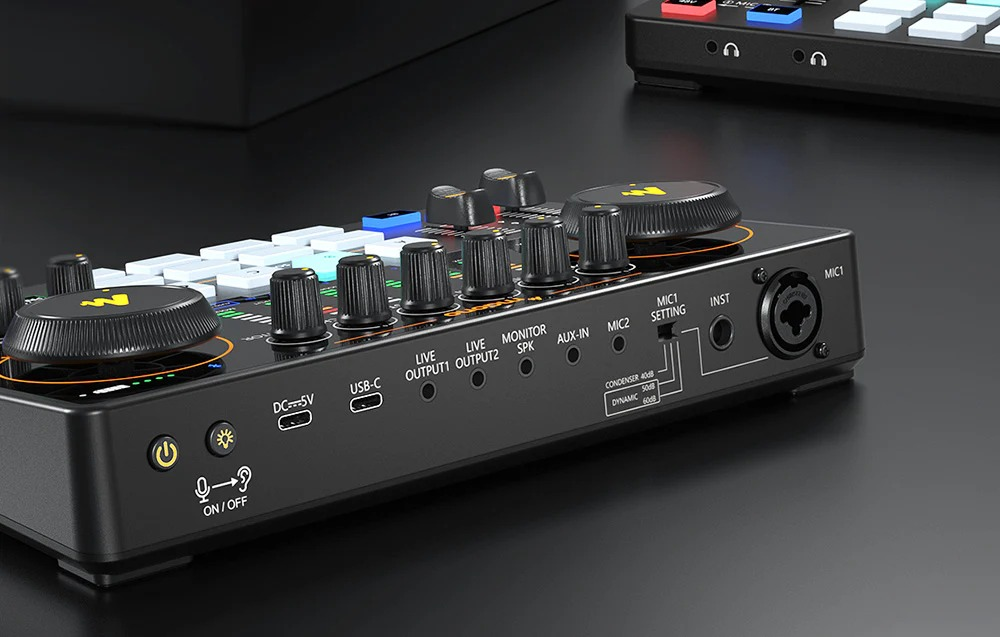 Un mixer audio nero con varie manopole, porte e pulsanti su una superficie scura.
