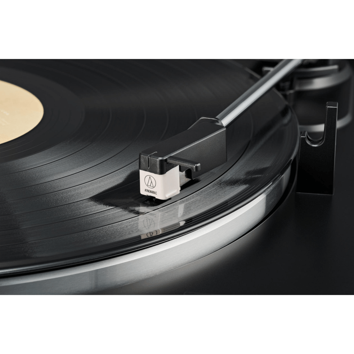 Un giradiscos reproduce un disco de vinilo negro con el brazo y una cápsula blanca apoyados en él.