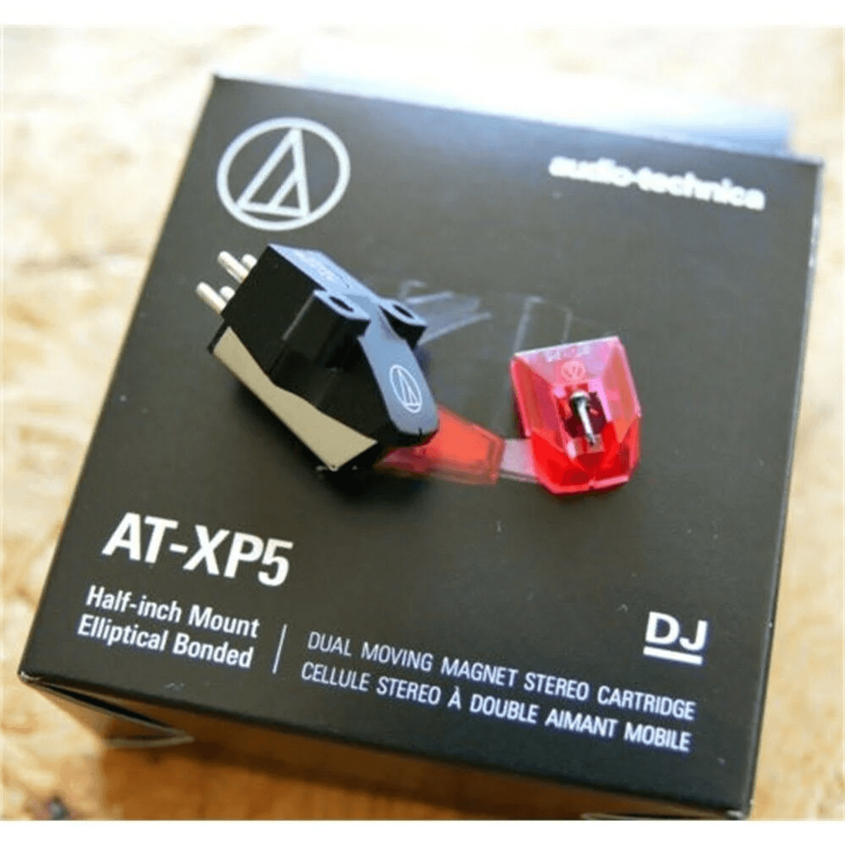 Cartucho de tocadiscos Audio-Technica AT-XP5 colocado sobre su caja de producto en blanco y negro.