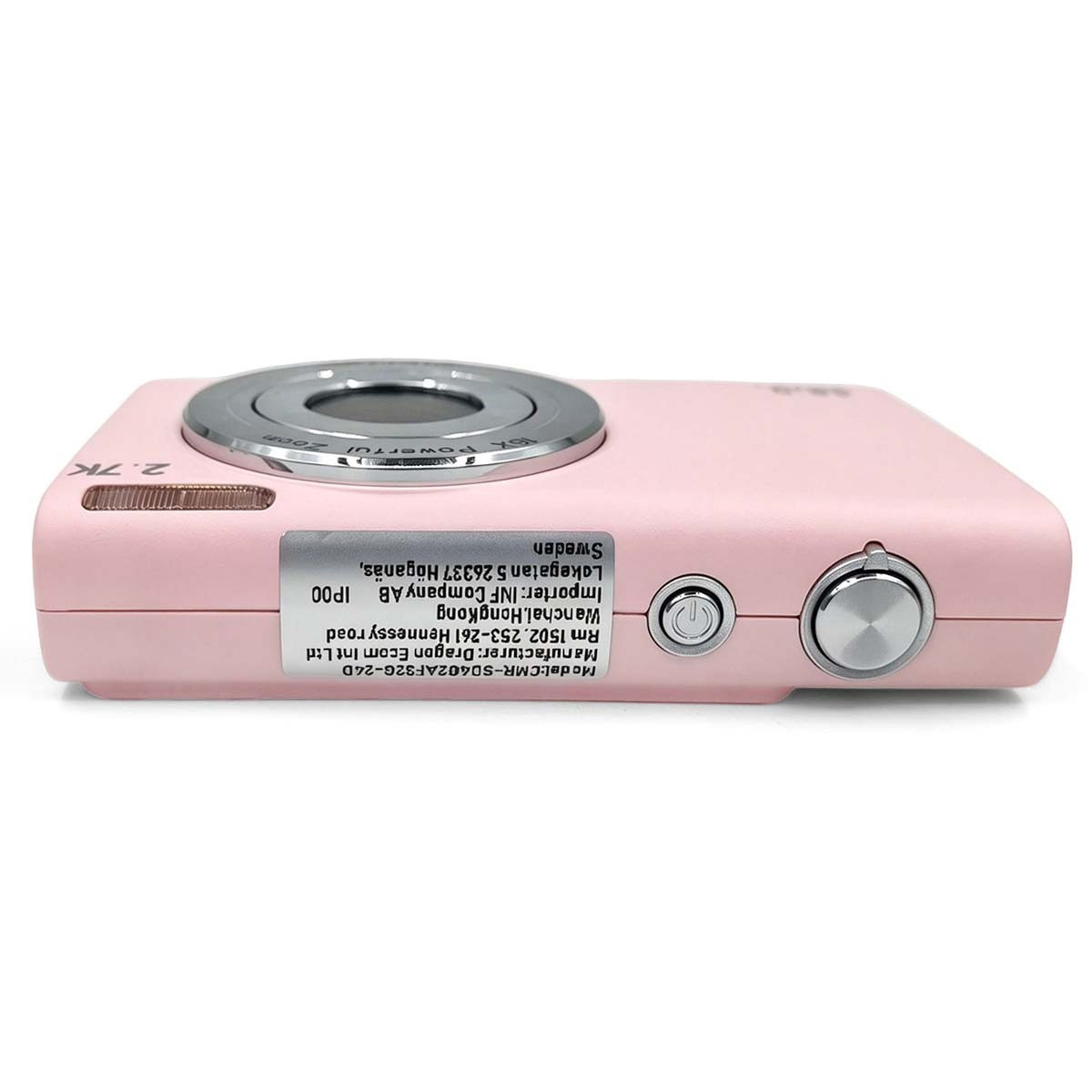 Una fotocamera digitale rosa poggia su sfondo bianco, con un adesivo sul fondo.