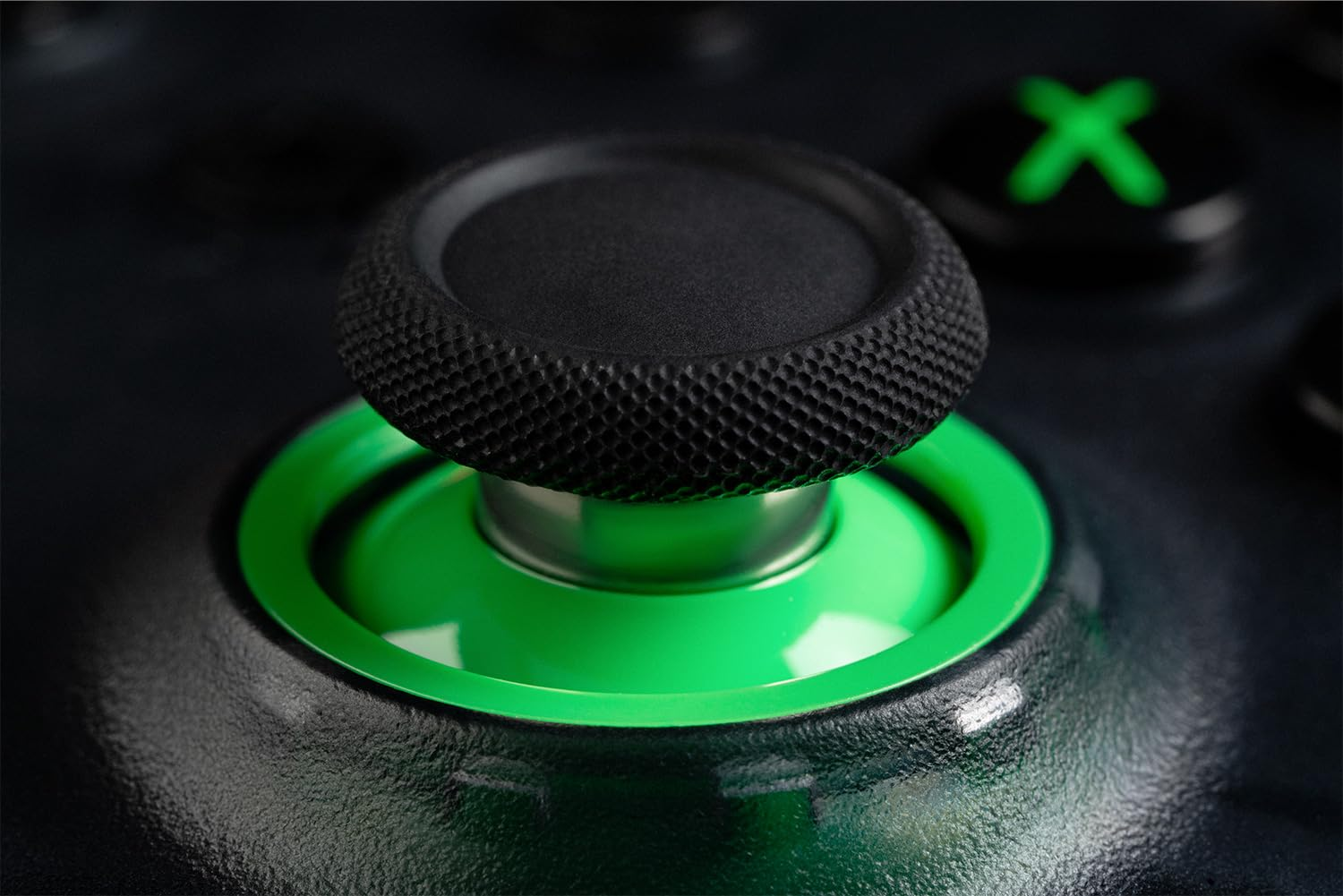 Zbliżenie czarnego joysticka z zieloną podstawą i świecącym zielonym przyciskiem w tle.