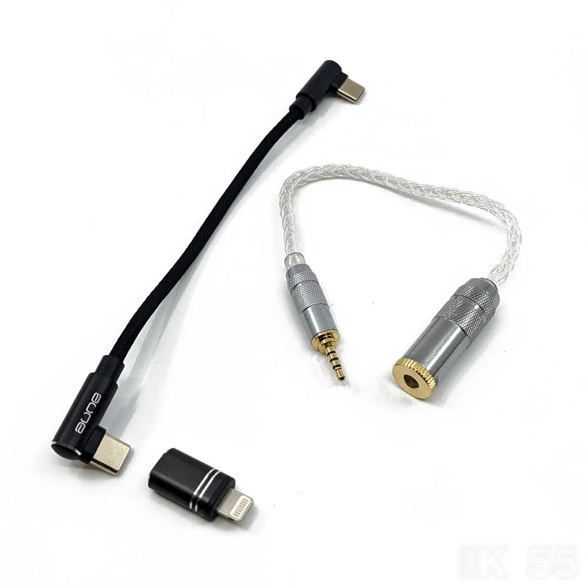 Un cable USB-C negro, un pequeño adaptador y un cable de audio plateado con conectores sobre fondo blanco.