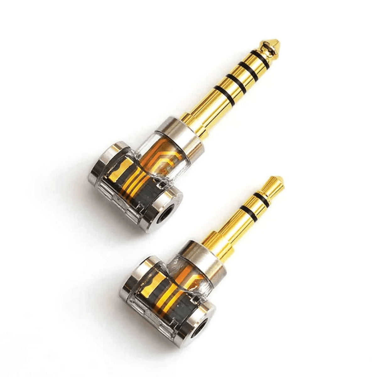 Dos adaptadores de audio chapados en oro con carcasas transparentes y circuitos visibles sobre fondo blanco.