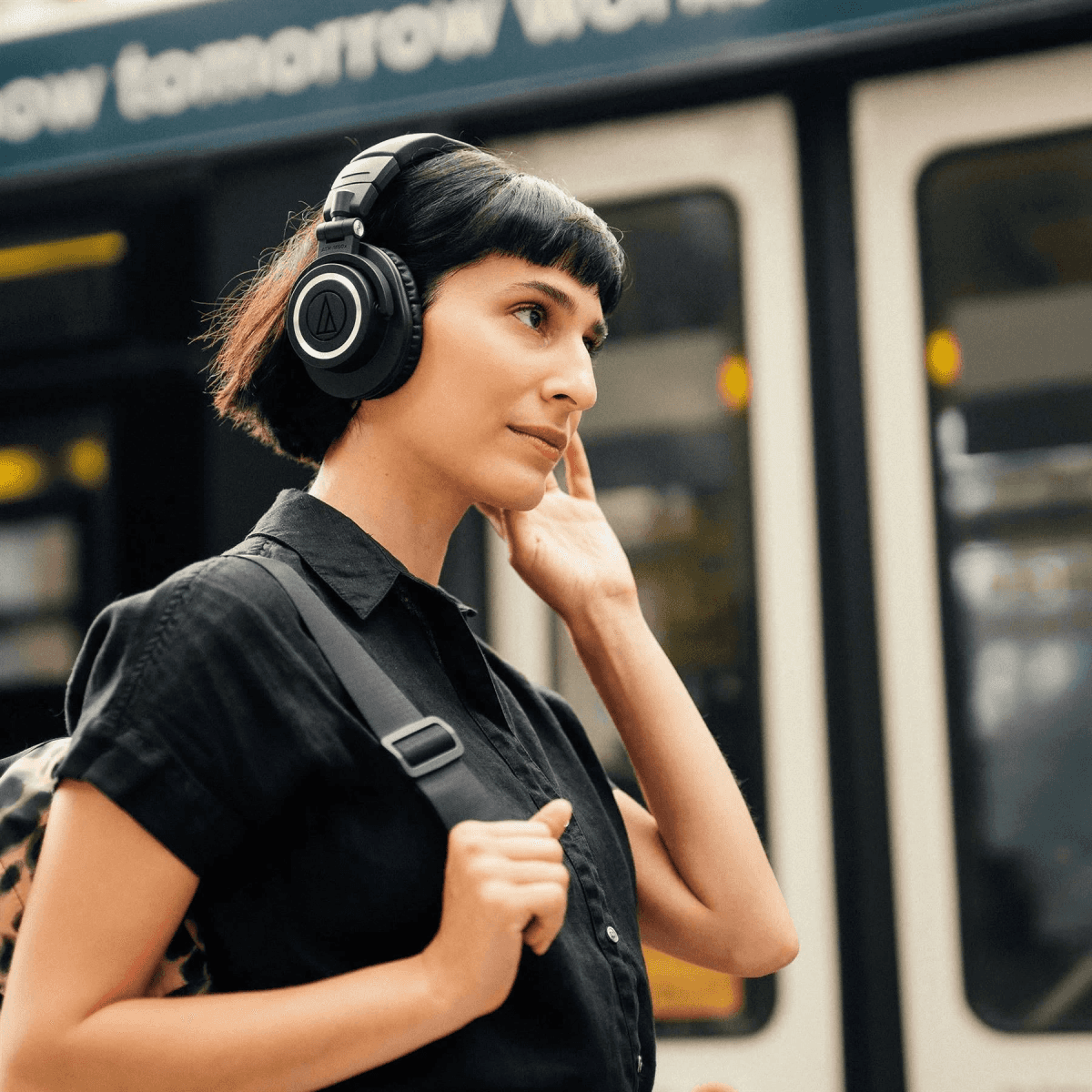 Una donna con i capelli neri corti indossa cuffie nere e una camicia nera all'aperto.