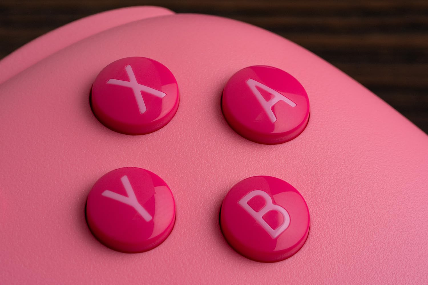 Primo piano dei pulsanti rosa X, A, Y e B su un controller rosa chiaro.