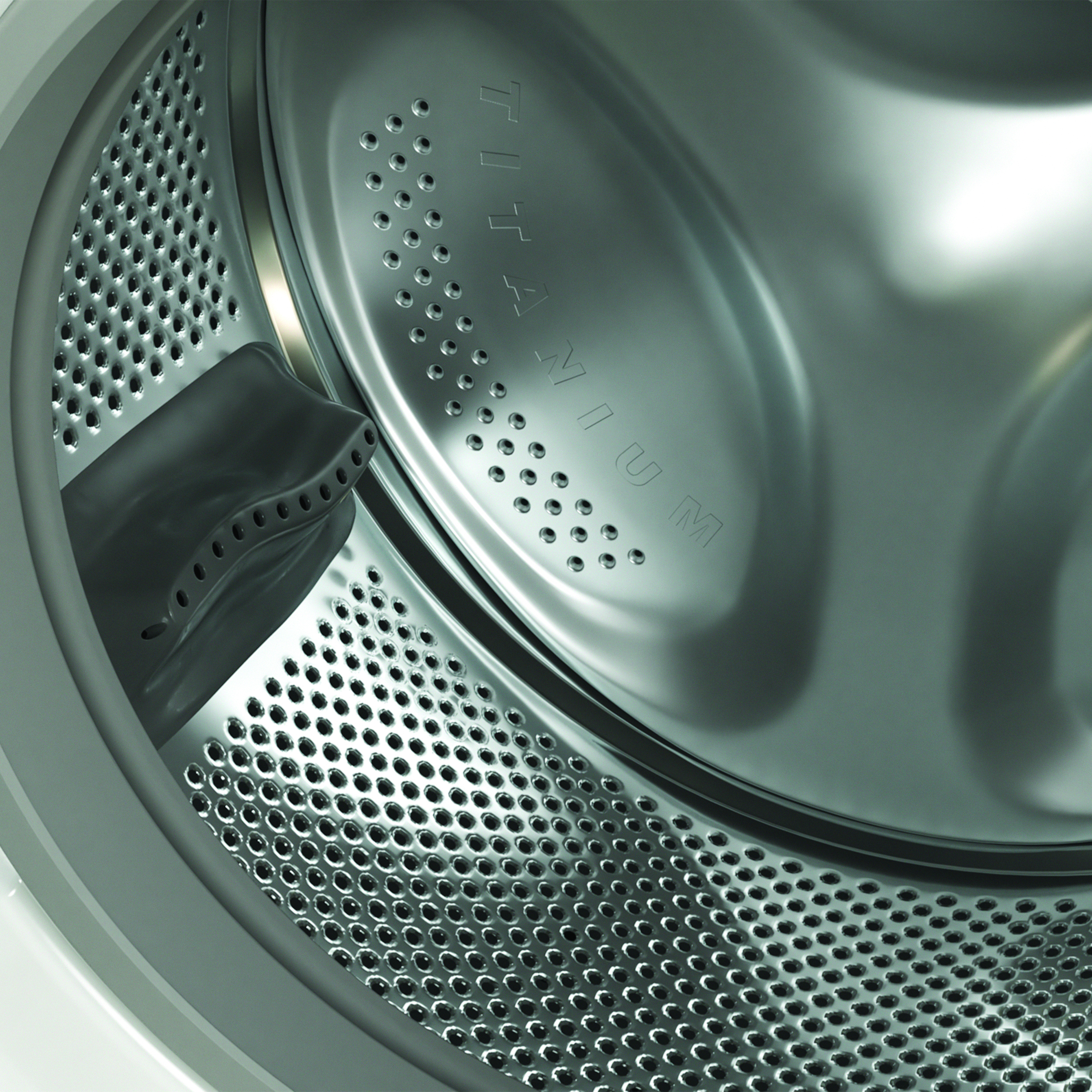 L'interno del cestello di una lavatrice argentata con molte perforazioni e la scritta Titanium.