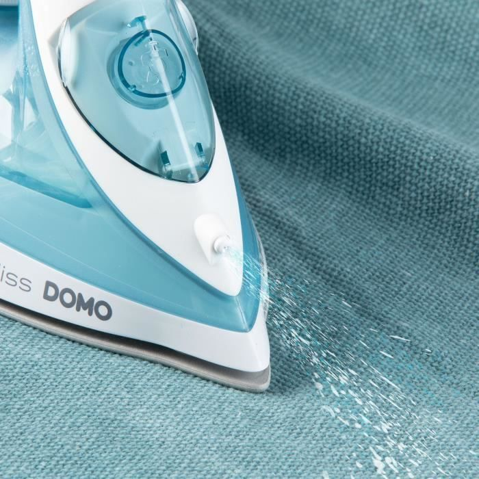 Ein weiß-türkises Dampfbügeleisen sprüht Wasser auf einen blauen Stoff.