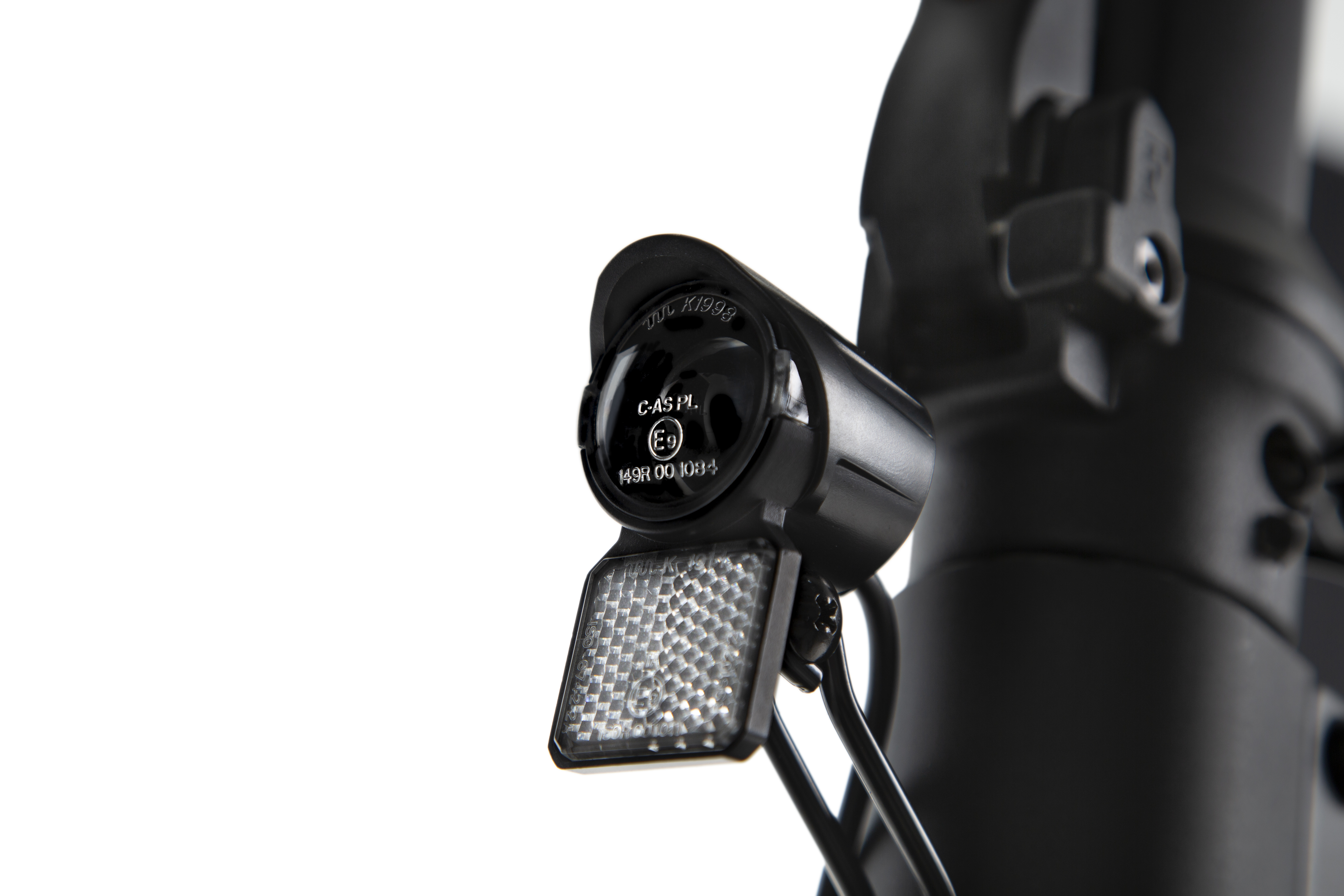 Un faro negro para bicicleta eléctrica con reflector integrado está montado en la potencia del manillar, fondo blanco.