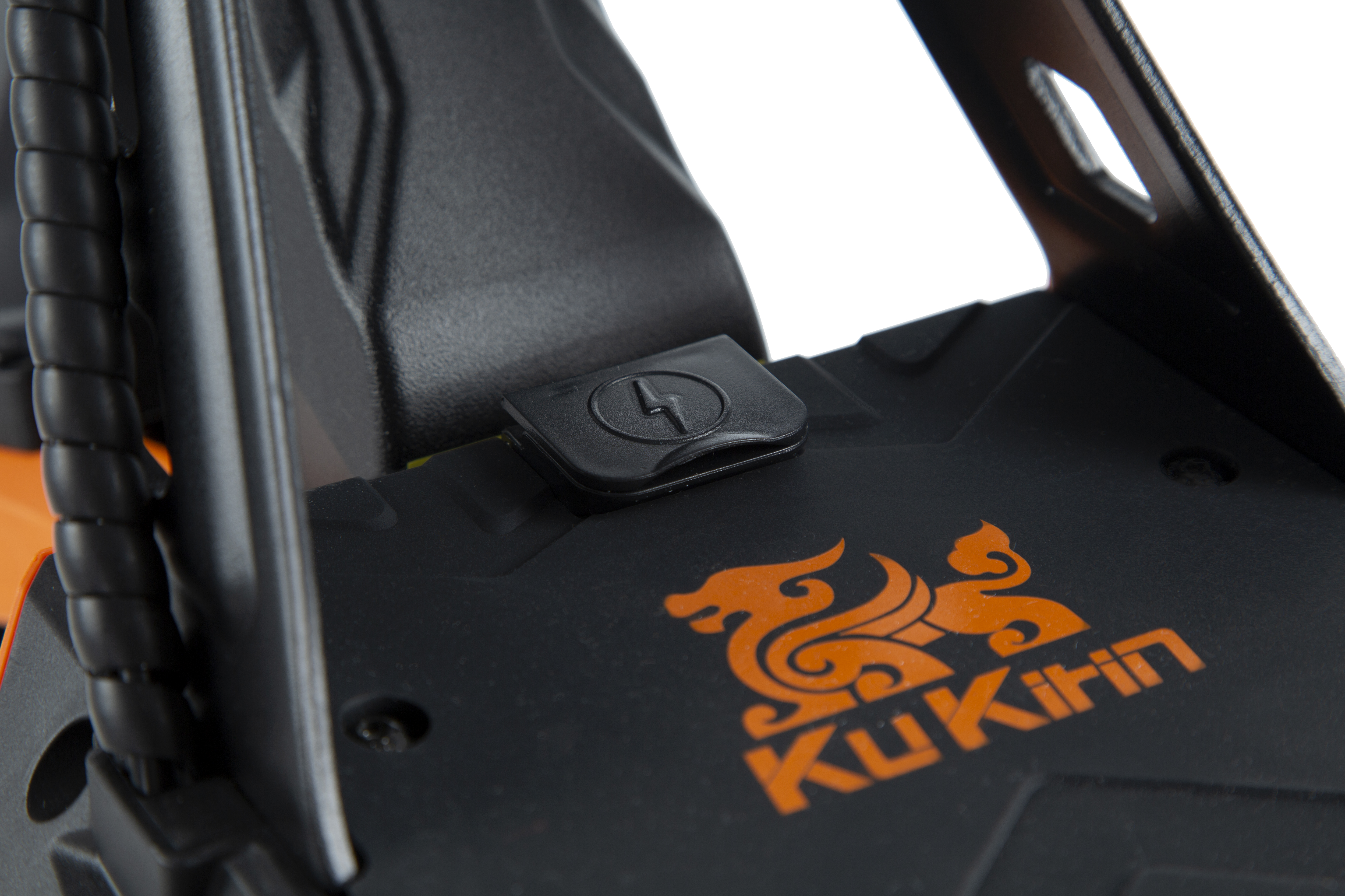 Primer plano de una tabla de patinete KuKirin negra con un logo de dragón naranja y un puerto de carga.