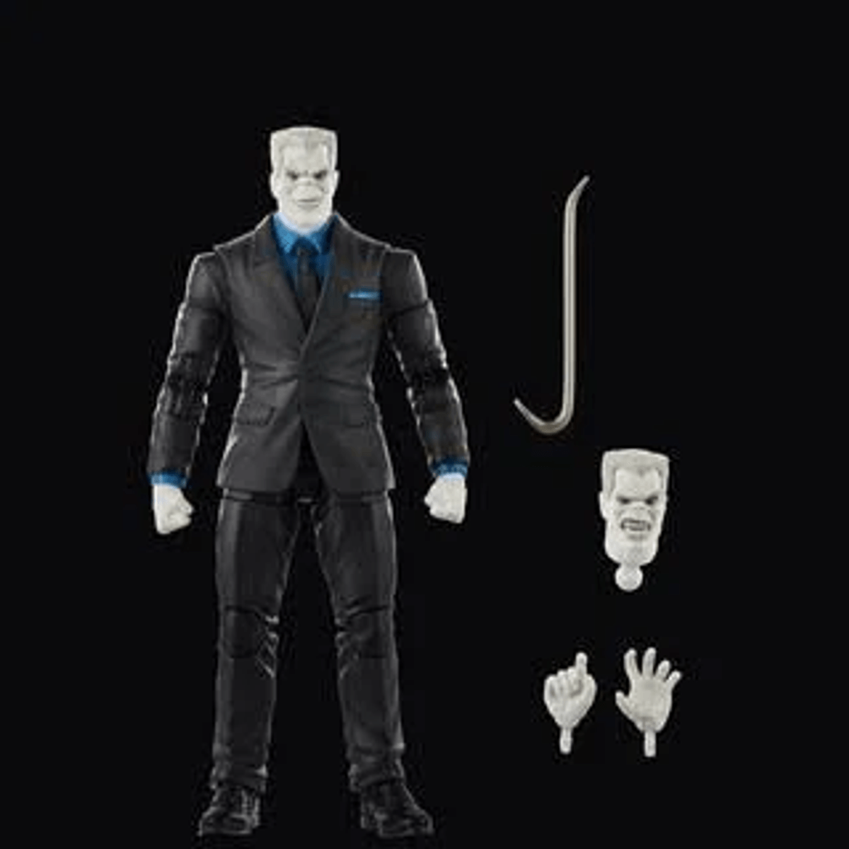 Action figure grigia in abito con testa, mani intercambiabili e piede di porco su sfondo nero.