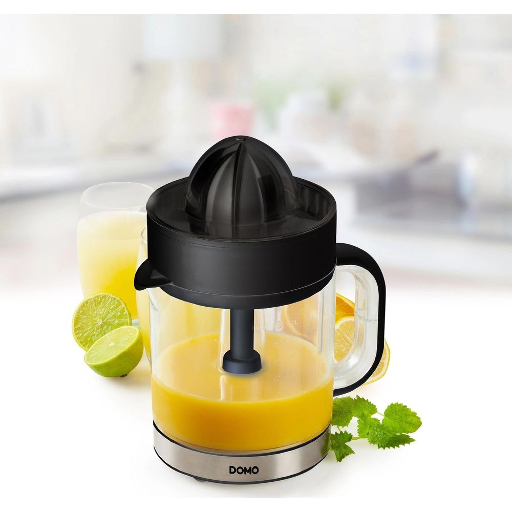 Spremiagrumi elettrico nero con contenitore pieno di succo, circondato da lime e limoni su un bancone.