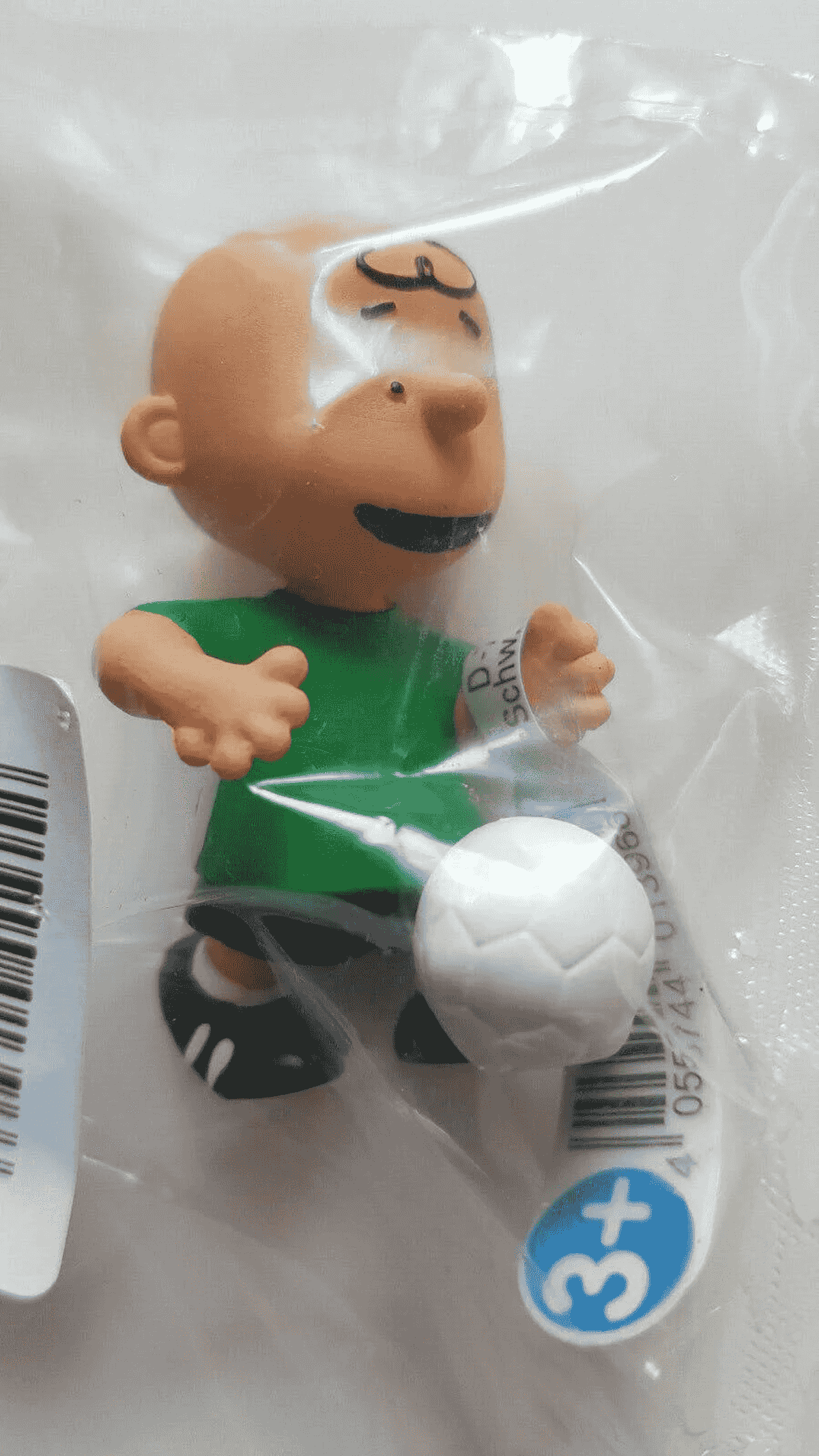 Statuetta giocattolo di Charlie Brown con maglietta verde e pantaloncini neri, con un pallone da calcio, in plastica.
