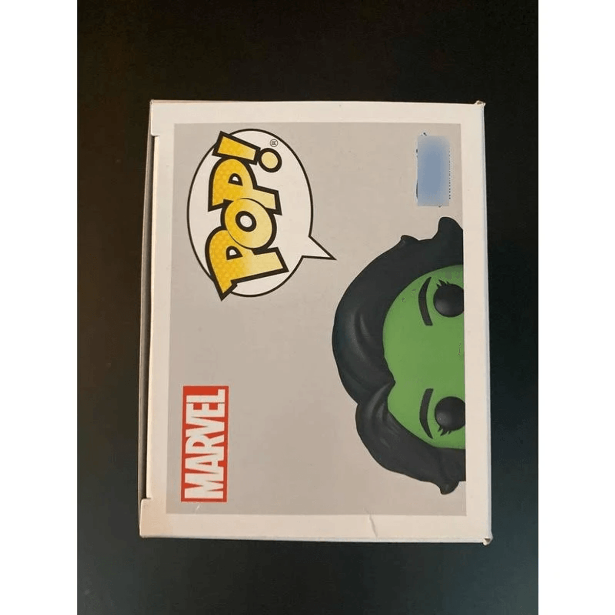 Una scatola da collezione Pop Marvel mostra la testa verde di un personaggio femminile con capelli neri.