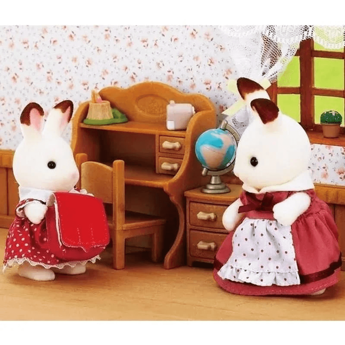Dos conejitos de juguete en vestidos están en una habitación en miniatura con un escritorio y globo.