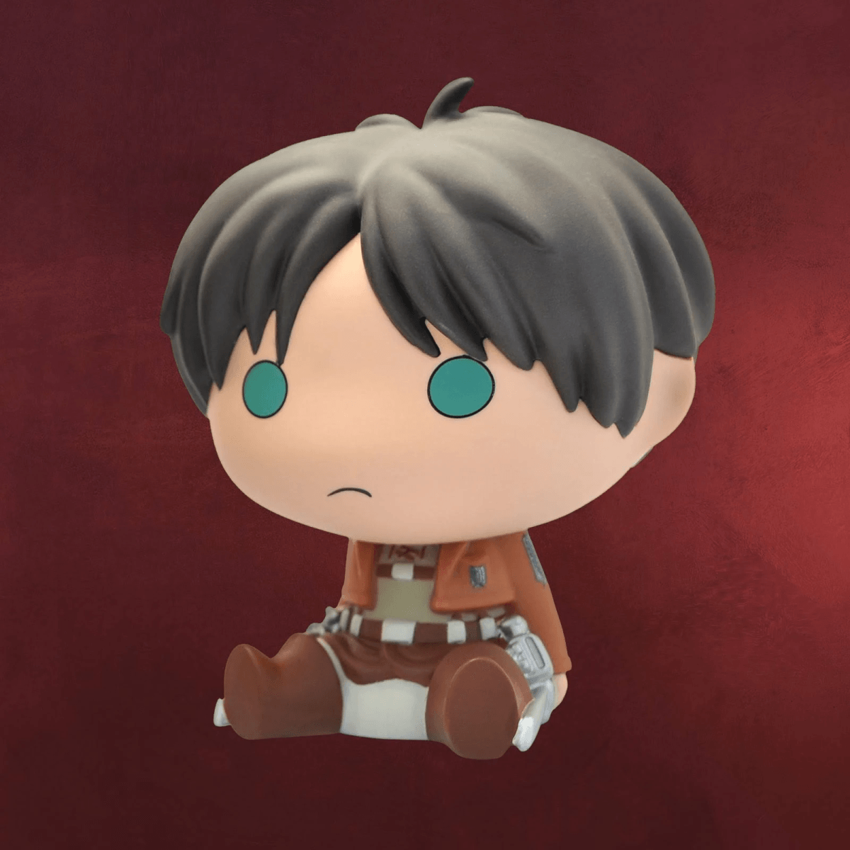 Eine niedliche Chibi-Figur von Eren Jaeger mit großen runden Augen und Uniform, vor rotem Hintergrund.